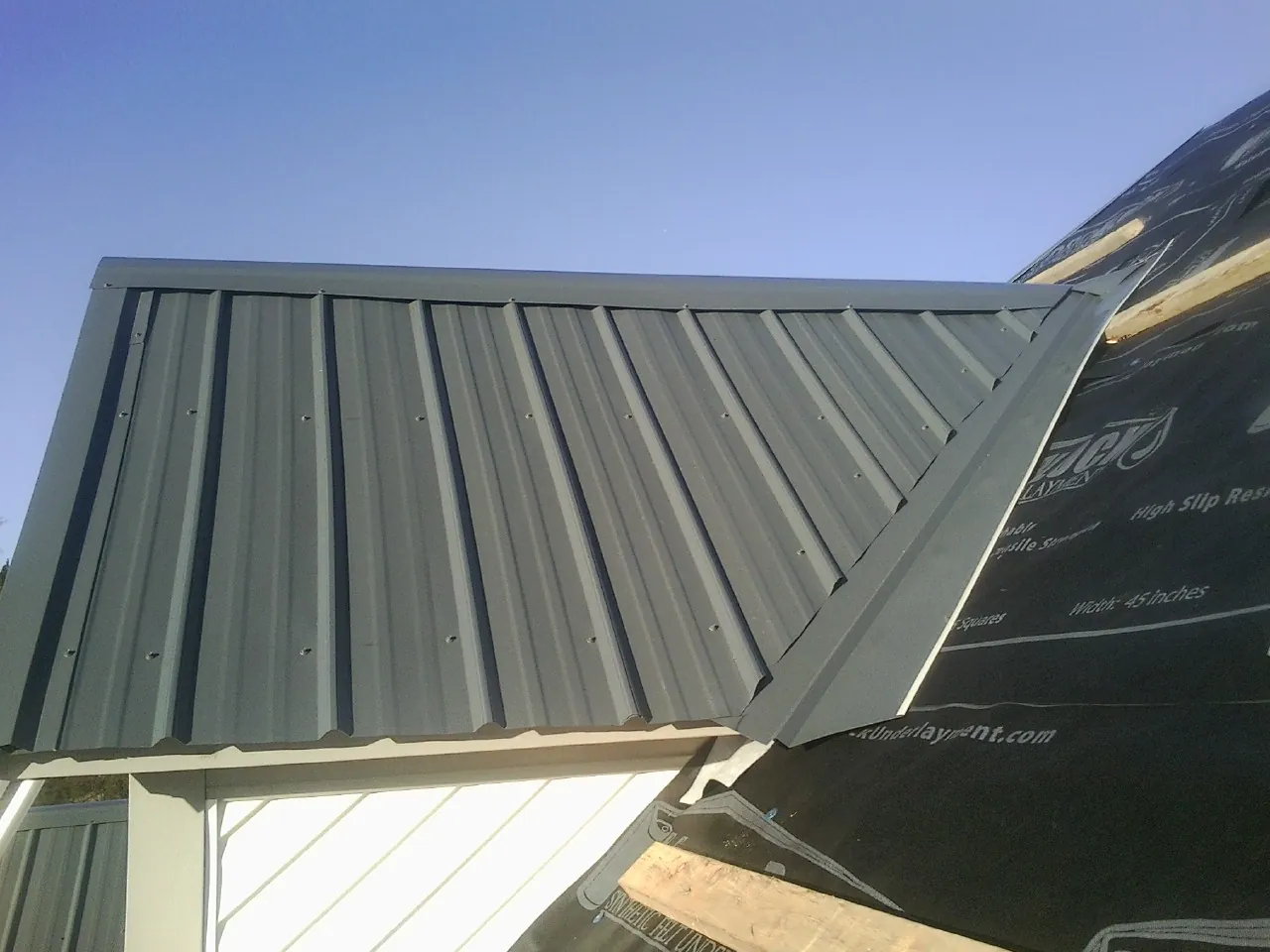 Gray metal roof panels going on over a garage gable in Augusta